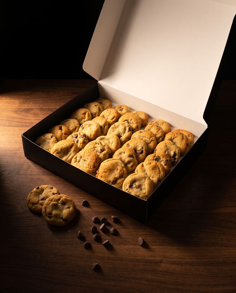 An open black box of bite-size chocolate chip Cravelits on a dark table
