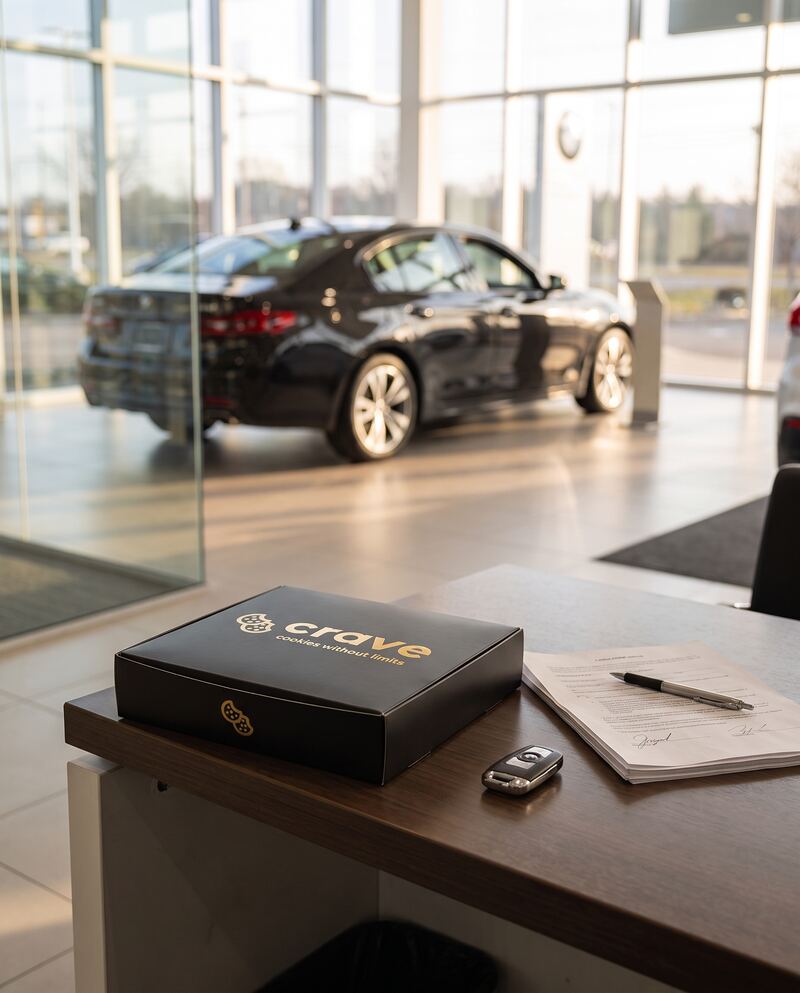 A closed Crave box on a dealership sales desk beside a car key and paperwork